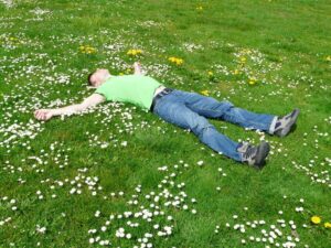 Person lying on the grass, enjoying peaceful rest and rejuvenation in nature to restore their well-being.